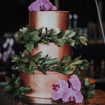 Bolo de aniversário de luxo decorado com flores rosas e folhagem.